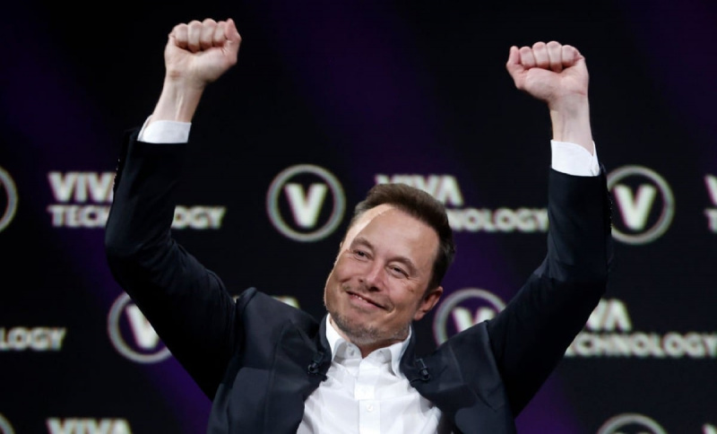  Elon Musk levanta los brazos triunfante.