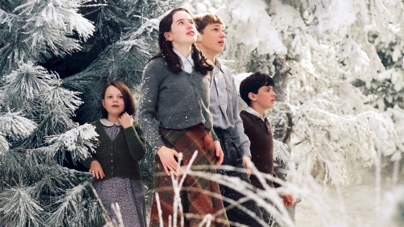   Cuatro niños se paran en un paisaje nevado, mirando a su alrededor con asombro.
