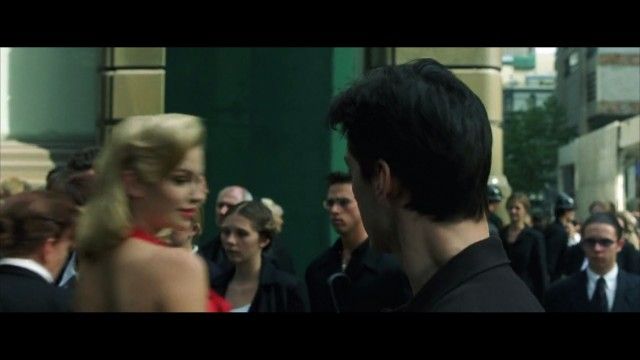 Neo ve a la mujer del vestido rojo.