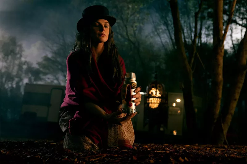   Şapkalı Gül (Rebecca Ferguson) bir mumun üzerinde diz çöküyor.'Doctor Sleep'