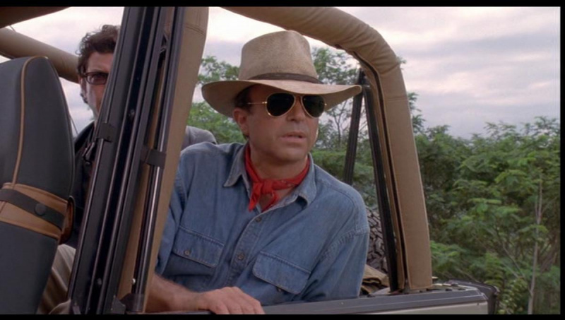   Белац у широкој федори и наочарима за сунце седи у џипу и гледа у даљину"Jurassic Park"