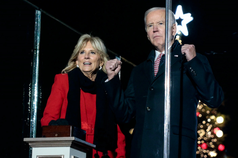  Jill y Joe Biden miran intensamente frente a ellos con un gran árbol de Navidad al fondo.