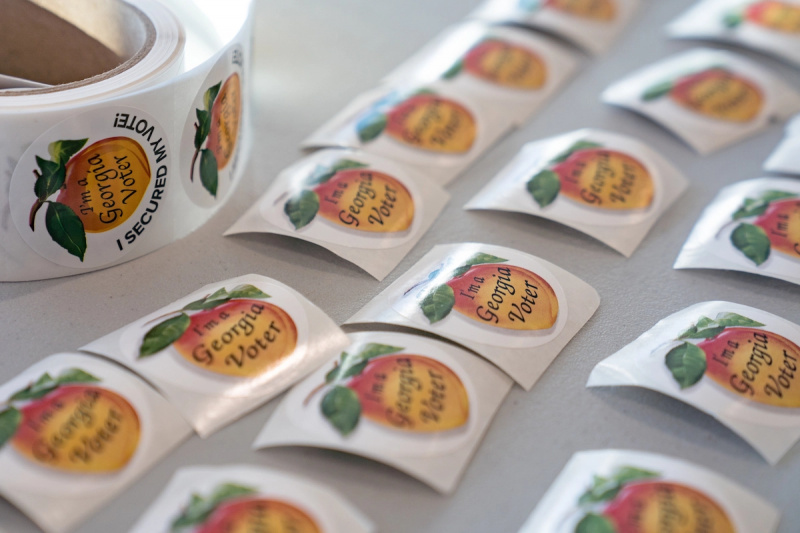  Una mesa con calcomanías de votantes de Georgia en un logotipo de melocotón