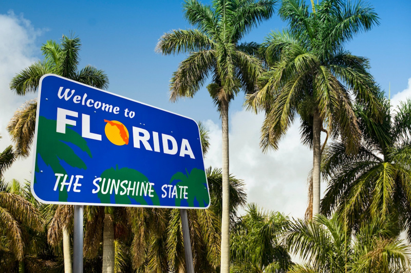   Una lectura de señales de tráfico"welcome to Florida" with palm trees behind it.