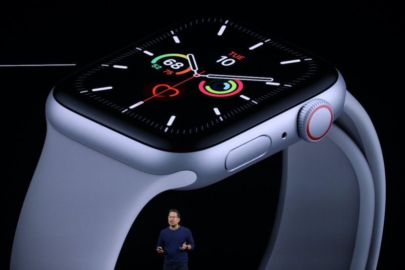   Un hombre (Stan Ng) se ve muy pequeño en primer plano frente a una proyección gigante de un Apple Watch detrás de él.