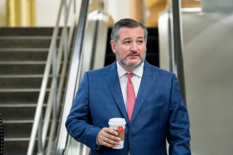   Ted Cruz camina solo por el Capitolio sosteniendo una taza de café.