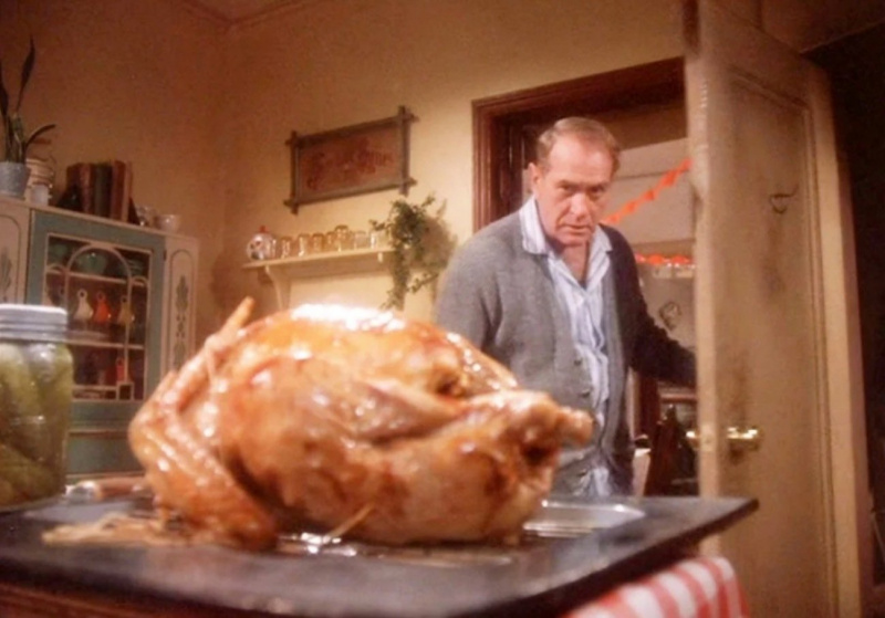   Un hombre mayor observa un delicioso pavo sentado en la mesa de la cocina en una escena de A Christmas Story.