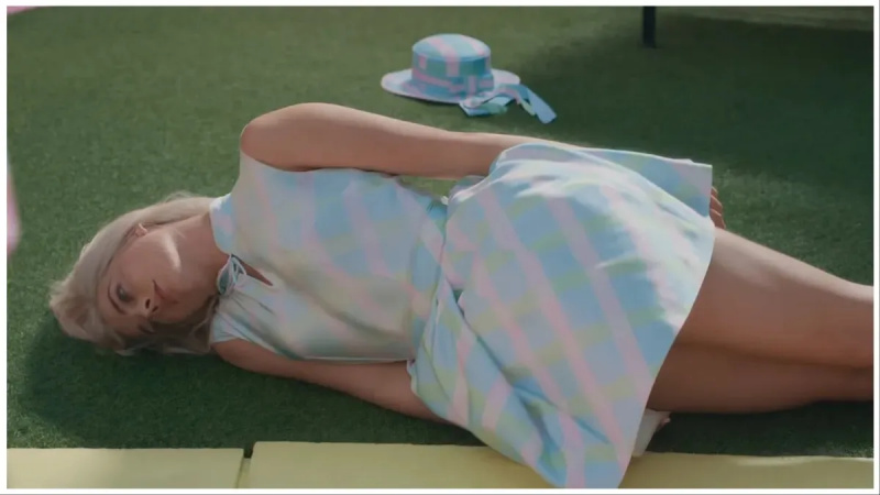   Barbie (Margot Robbie) yace en el suelo de costado, derrotada en'Barbie'.