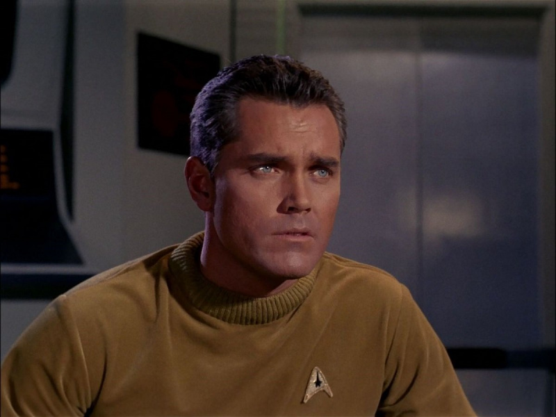   Jeffrey Hunter como el Capitán Christopher Pike en el no emitido'Star Trek' pilot, "The Cage." He is a white man with black hair wearing a gold Starfleet shirt. He looks concerned.